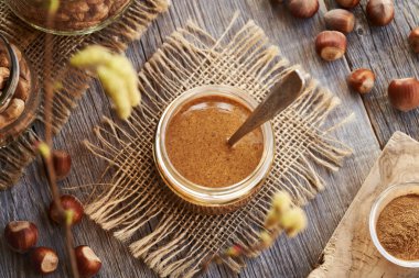 Ahşap bir masada cam bir kavanozda ev yapımı fındık ezmesi, üst manzara. Sağlıklı vejetaryen yemeği..