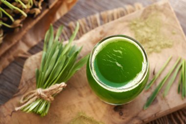 Taze yeşil arpa suyu ve ahşap bir masada yetiştirilmiş bıçaklar.