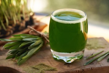 Bir bardak taze, yeşil arpa tohumu suyu ve ev yapımı bıçaklar.
