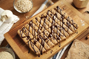 Beyaz protein tozu, yulaf gevreği, susam şurubu, akçaağaç şurubu, tarçın ve vanilya ile yapılmış ev yapımı sağlıklı atıştırmalıklar.