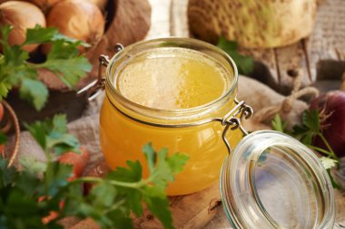 Bardak kavanozunda tavuk çorbası ya da kemik suyu. Taze maydanoz, soğan ve arka planda kereviz kökü.