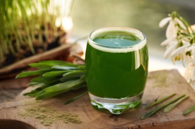 Yeşil arpa çim suyu, cam bir fincanda taze yapraklarla.