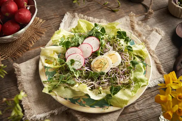 Bahar ayında taze sebze salatasında yeşil bezelye ve turp filizleri ile masada yumurtalar.