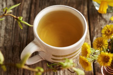 Taze yaka çiçekli bir bardak tay ayağı çayı.