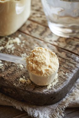 Şeffaf ölçüm kabında bir bardak suyla birlikte beyaz protein tozu.