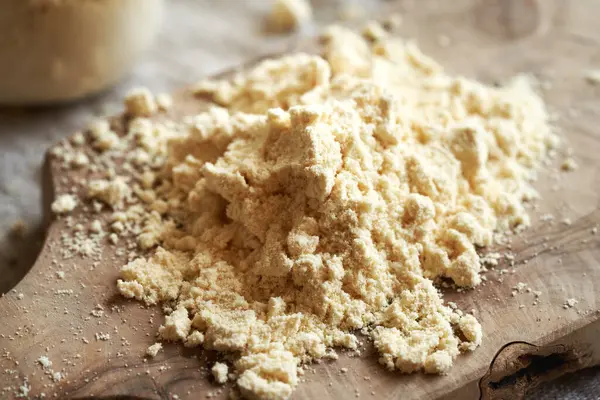 Tahta bir masanın üzerinde bir yığın beyaz protein tozu.