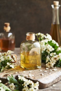 Bir şişe bitkisel tentür. Baharda bir masada taze dikenli çiçekler.