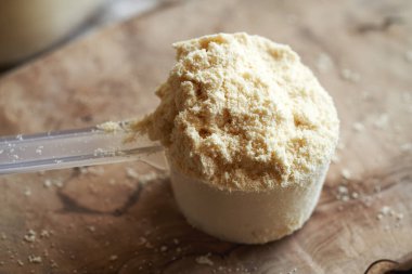 Masadaki plastik ölçü kabında beyaz protein tozu.