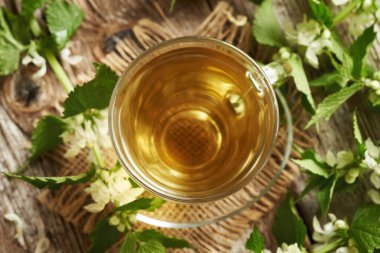 Taze beyaz ısırgan otu çiçekleri ve yaprakları bir fincan bitkisel çayla, üst manzara