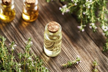 Tahta bir masanın üzerinde şeffaf bir kekik yağı şişesi.