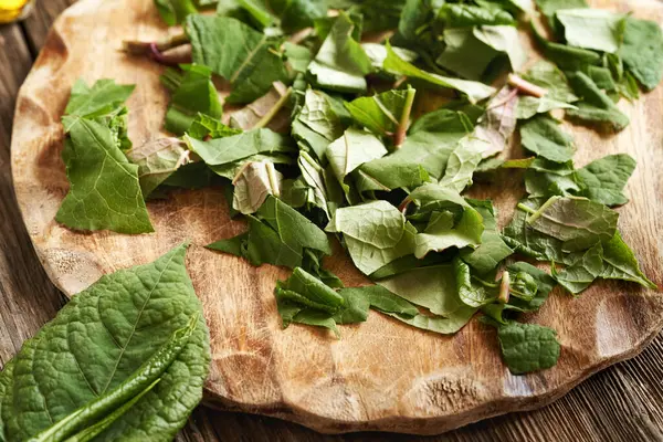 Doğranmış Japon düğümü ya da Reynoutria japonica ağaç kesim tahtasının üzerinde yapraklar - bitkisel tentürler için malzeme