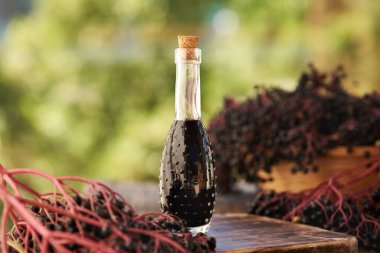 Doğada taze yaban mersinli bir şişe siyah yaşlı şurubu.