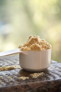 Açık havada plastik bir kaşık içindeki beyaz protein tozu.