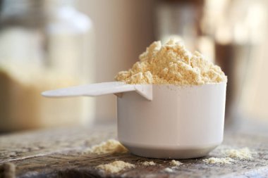 Masadaki beyaz kaşık içinde beyaz protein tozu.