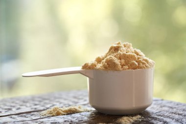 Ölçüm kepçesinde beyaz protein tozu ile yeşil bokeh arkaplan, kopyalama alanı