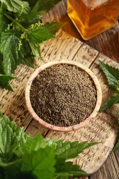 Masasında taze yapraklar olan bir kasede ısırgan otu tohumları.