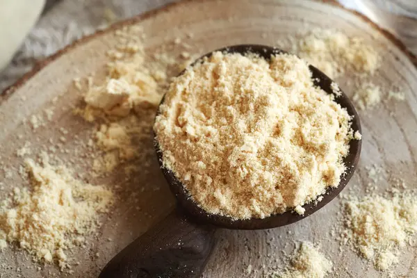 Masadaki tahta kaşıkta beyaz protein tozu.