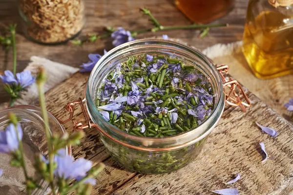 Sehpadaki cam kavanozda taze hindiba çiçekleri ve alkolden elde edilen bitkisel tentürlerin hazırlanması