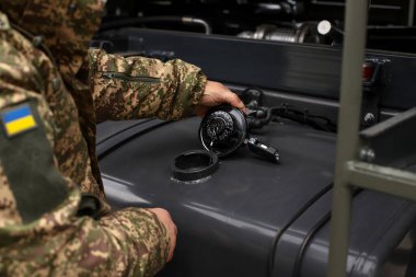 Bir adam benzin deposunun kapağını açıp yakıt ikmali yapıyor..