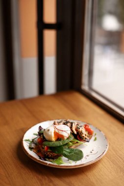 Kahverengi bir tabakta kızarmış ekmek sandviç, guacamole, kırmızı balık, yumurta ve yeşillikler.