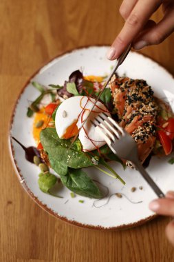 Kahverengi bir tabakta kızarmış ekmek sandviç, guacamole, kırmızı balık, yumurta ve yeşillikler.