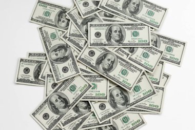 Birçok Amerikan yüz dolarlık banknotlar beyaz bir arka planda rastgele masanın üzerinde yatıyor.