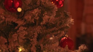 Karlı bir Noel ağacı parlak kırmızı süslemeler ve sıcak festival ışıklarıyla süslenmiş, samimi ve neşeli bir tatil havası yaratıyor.. 