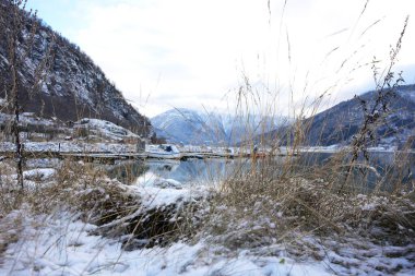Norveç 'in Gaupne şehrinde karla kaplı dağları, sakin suları ve fiyortların kıyısına yanaşmış tekneleri olan manzaralı bir kış marinası.. 