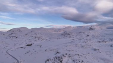 Norveç 'te kayan tepeler, engebeli zirveler ve dramatik bulutlu kış gökyüzü içeren nefes kesici karlı bir plato. Uçsuz bucaksız Kuzey Kutbu el değmemiş güzellikleri, sakin manzaraları sergiliyor.