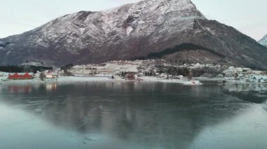 Huzurlu bir Norveç köyü sakin bir fiyort ve yüksek karlı dağlar arasında sessizce oturur, göz kamaştırıcı kış manzarası sergiler.