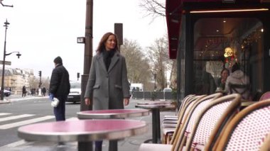 Paris, Fransa 12.21.2024 Bir kadın Paris 'te klasik bir kafenin önünden geçiyor ve Paris sokak hayatı ve kültürünün cazibesini yakalıyor.. 