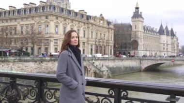 Paris 'in tarihi köprüsünde poz veren zarif bir kadın Seine Nehri manzaralı muhteşem bir şehir manzarası var..