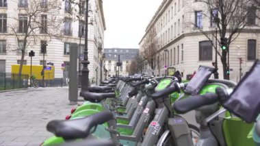 Paris, Fransa 12.21.2024 Paris caddesinde çevre dostu şehir ulaşımını ve modern şehri sembolize eden düzgün düzenlenmiş bir sıra yeşil motorsiklet.. 