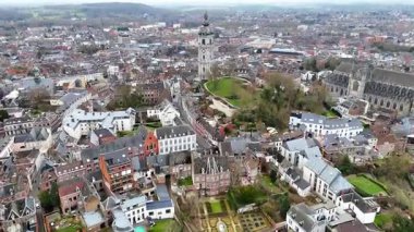 Mons, Belçika 'nın çarpıcı hava manzarası, UNESCO listesindeki çan kulesi, tarihi binalar, yeşil park alanları ve bulutlu bir gökyüzü altında panoramik bir şehir..
