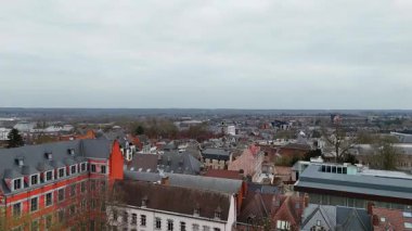 Bulutlu, gri bir günde Belçika 'nın Mons şehrinin manzarası tarihi mimarisini, çatılarını ve şehir manzarasını bulutlu bir gökyüzü altında sergiliyor..