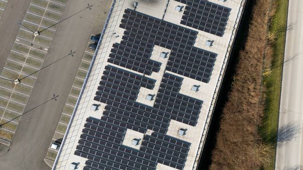 Detailed aerial shot of a rooftop in Epernay, France, featuring a grid of solar panels, adjacent parking spaces, and a nearby road.