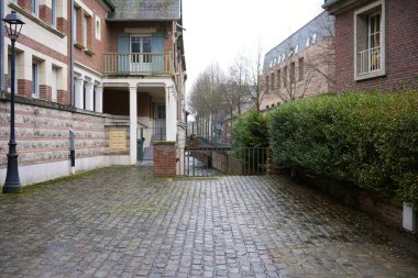Amiens, Fransa 'da sakin bir kaldırım yolu. Tarihi tuğla binalar, yeşil çitler ve arka planda büyüleyici bir manzara yaratan bir kanal var.