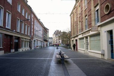 View of a peaceful pedestrian street featuring benches, brick buildings, and a modern urban layout on a clear day.  clipart