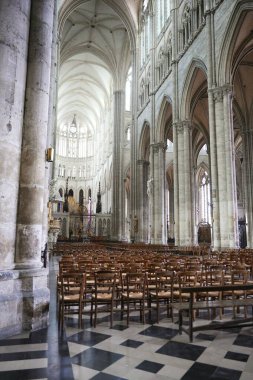 Zarif Gotik katedral iç mimarisi ahşap sandalyeler, yüksek sütunlar, sivri kemerler ve karmaşık vitray pencereler sergiliyor..