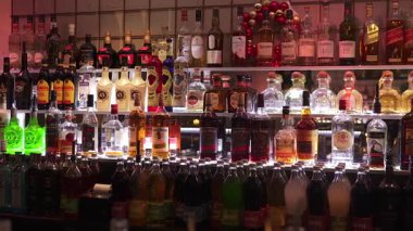 Geniş bir bar manzarası geniş bir içki ve içki şişelerini sergiliyor, şık bir şekilde raflarda düzgünce düzenleniyor. Münih, Almanya 31.12.2024