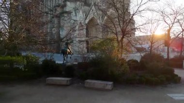 Fransa 'daki Reims Katedrali' nin çarpıcı bir gün batımı manzarası, önplanda bir binicilik heykeli, gotik mimari ve huzurlu bir kent manzarası yer alıyor..