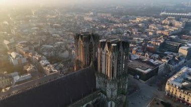 Şafak vakti Reims Katedrali üzerinde nefes kesen dairesel bir uçuş gotik mimarisini ve uyanan şehrin panoramik manzarasını sergiliyor..