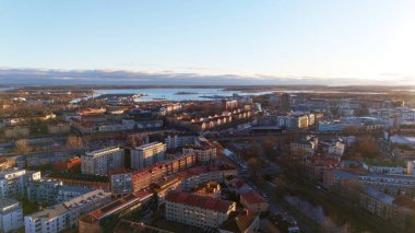 Günbatımında İsveç 'in Karlstad kentinin güzel bir hava manzarası, şehir manzarası, su yolları ve binalara ve manzaralı rıhtıma yansıyan altın güneş ışığı..