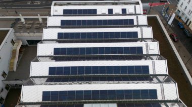 Günümüz ortamında yenilenebilir enerji çabaları ve sürdürülebilir kentsel gelişimin vurgulandığı, güneş panelleriyle kaplı büyük bir çatıya tepeden aşağı bakış. 