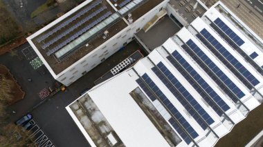 Güneş panelleri yüklü, kentsel bir ortamda sürdürülebilir enerji çözümleri ve modern altyapı gösteren çoklu çatıların yukarıdan aşağı görünümü.
