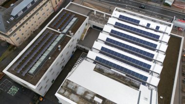 Çatılarına güneş panelleri monte edilmiş, sürdürülebilir enerji çözümleri ve çevre dostu kentsel altyapı gösteren çoklu binaların yüksek açılı görüntüsü.