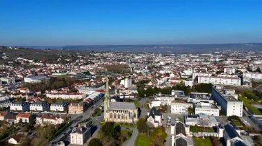 Epernay, Fransa 'nın yüksek açılı hava manzarası Gotik tarzı bir kilise, şehir mimarisi ve açık bir gökyüzünün altındaki üzüm bağlarını gösteriyor.. 