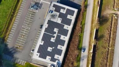 Bir İHA çatısı güneş panelleriyle donatılmış modern bir binaya doğru uçarak yenilenebilir enerji teknolojisi ve sürdürülebilir mimariyi yakalıyor..