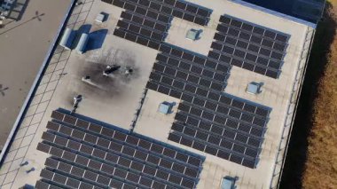 Güneş panellerini gösteren endüstriyel bir binanın çatısından yüksek açılı bir görüntü, alternatif enerji ve sürdürülebilirliğin kullanımını vurguluyor. 