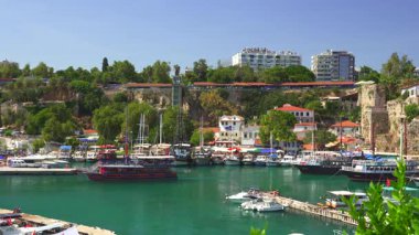 Antalya, Türkiye 11.02.2024 Turkuaz sular, demirli tekneler, yemyeşil ve kıyı boyunca tarihi binaların yer aldığı Eski Kent marinasının çarpıcı manzarası